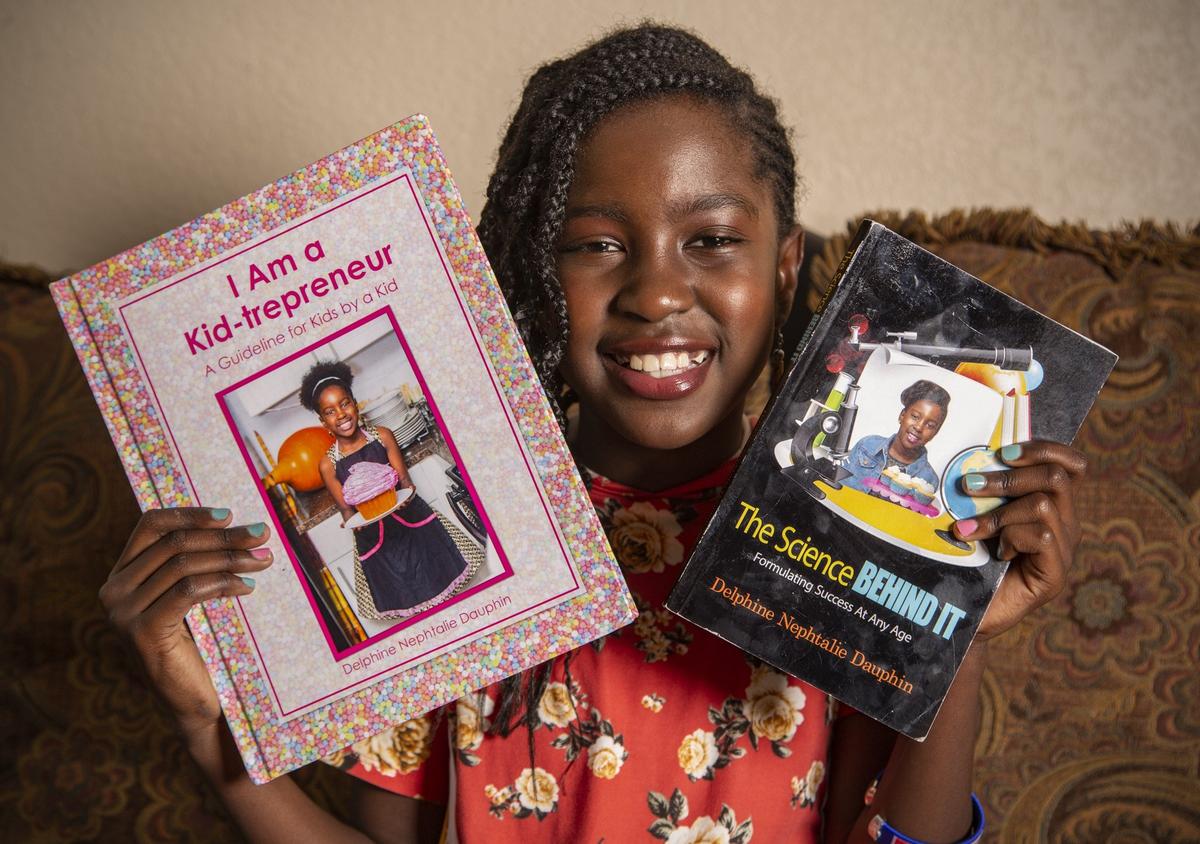 Delphine Nephtalie Dauphin, 10, shows the two books she has authored. Delphine has been the owner of her own cupcake business, Joy’s Yummy Cupcakes, for three years, starting from her Miramar home.