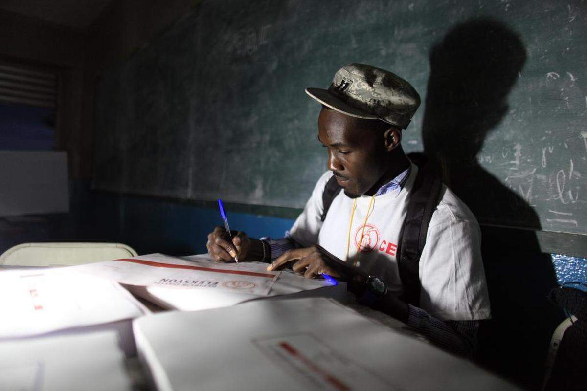 In this 2015 file photo, an electoral worker prepares election ballots by lamplight due to the electricity not working at the polling station in the Petion-Ville suburb of Port-au-Prince, Haiti, Sunday, Oct. 25, 2015.