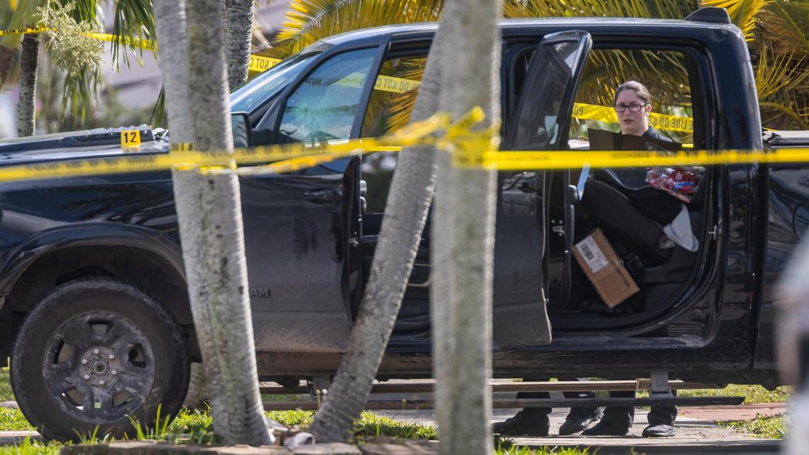 Investigators look inside a black pickup truck parked at a crime scene located near 1270 West 79th Street on Friday, Nov. 4, 2022, in Hialeah, Fla. Police say an off-duty Miami-Dade officer was shot by his ex-girlfriend during a domestic dispute Friday morning.
