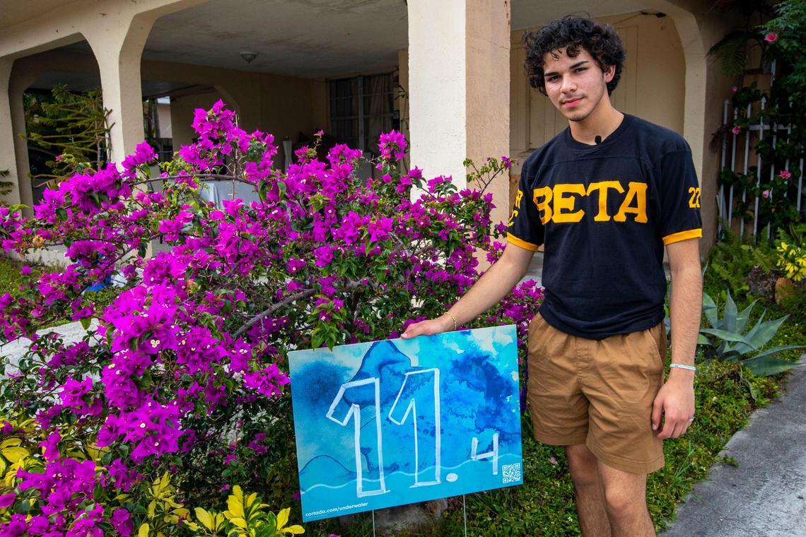 Rolando Morales, a senior at Miami Senior High, stands next to his Underwater Marker, which indicates his home’s elevation.