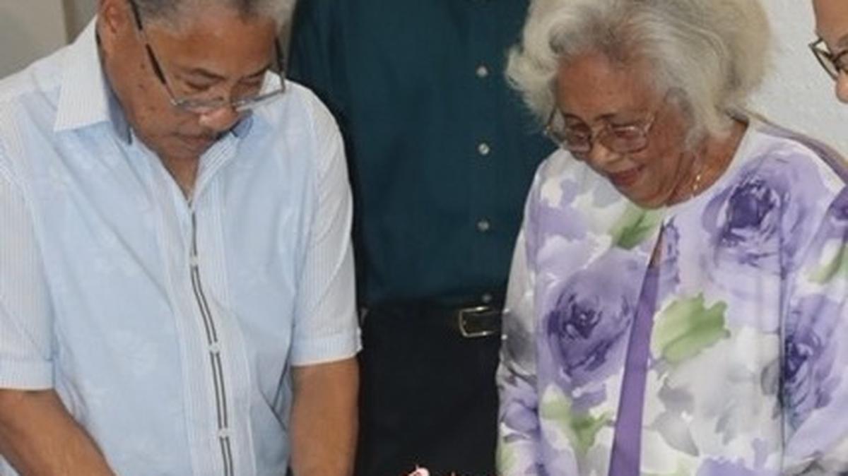 Isemenia Tai celebrates her 100th birthday with sons Richard Tai, cutting the cake, and Paul Tai. Courtesy of the Tai Family