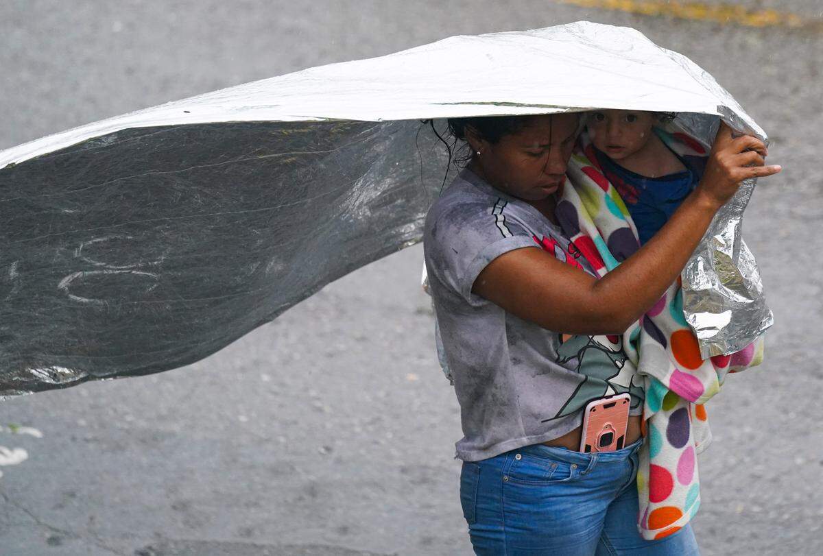 A Venezuelan migrant uses an emergency blanket as cover from the rain, near the banks of the Rio Grande in Matamoros, Mexico, Saturday, May 13, 2023.