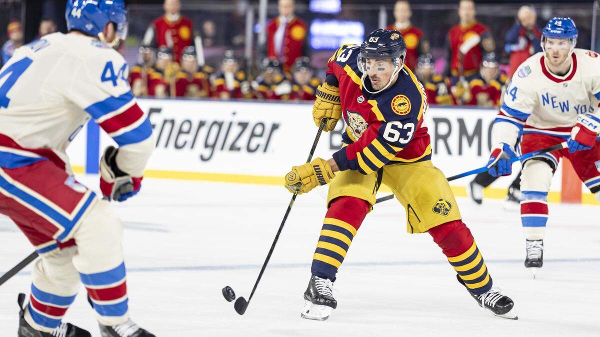 Florida Panthers left wing Brad Marchand (63) passes the puck as New York Rangers defenseman Vladislav Gavrikov (44) defends in the first period of their Winter Classic outdoor hockey game at loanDepot park on Friday, Jan. 2, 2026, in Miami, Fla.