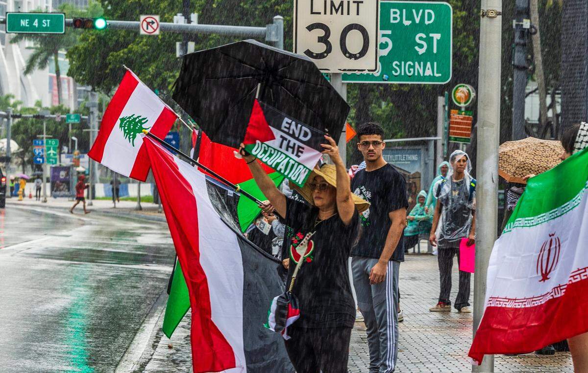 A woman shows a Palestinian flag with a message written on it during a Pro Palestinian demonstration in downtown Miami.