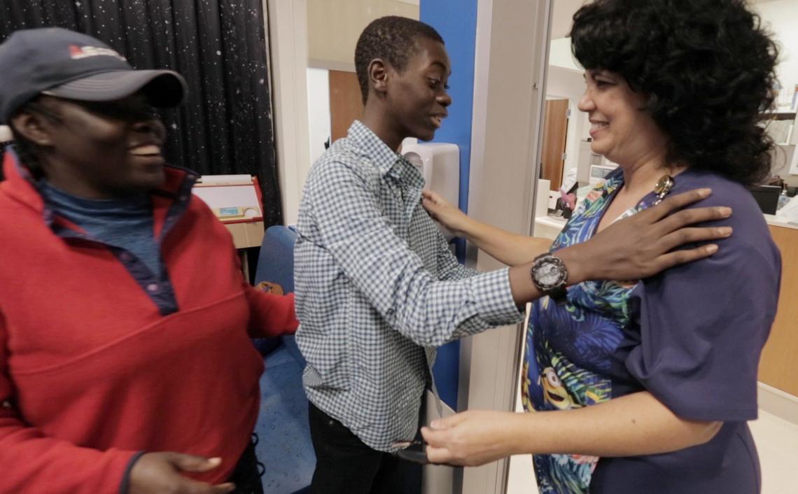 Djonsly Alcin (center), 14, and his mother Marie Belatrice Louis-Jean (left), 37, greet a Baptist Health nurse after arriving to get his weekly chemotherapy for a rare brain tumor.