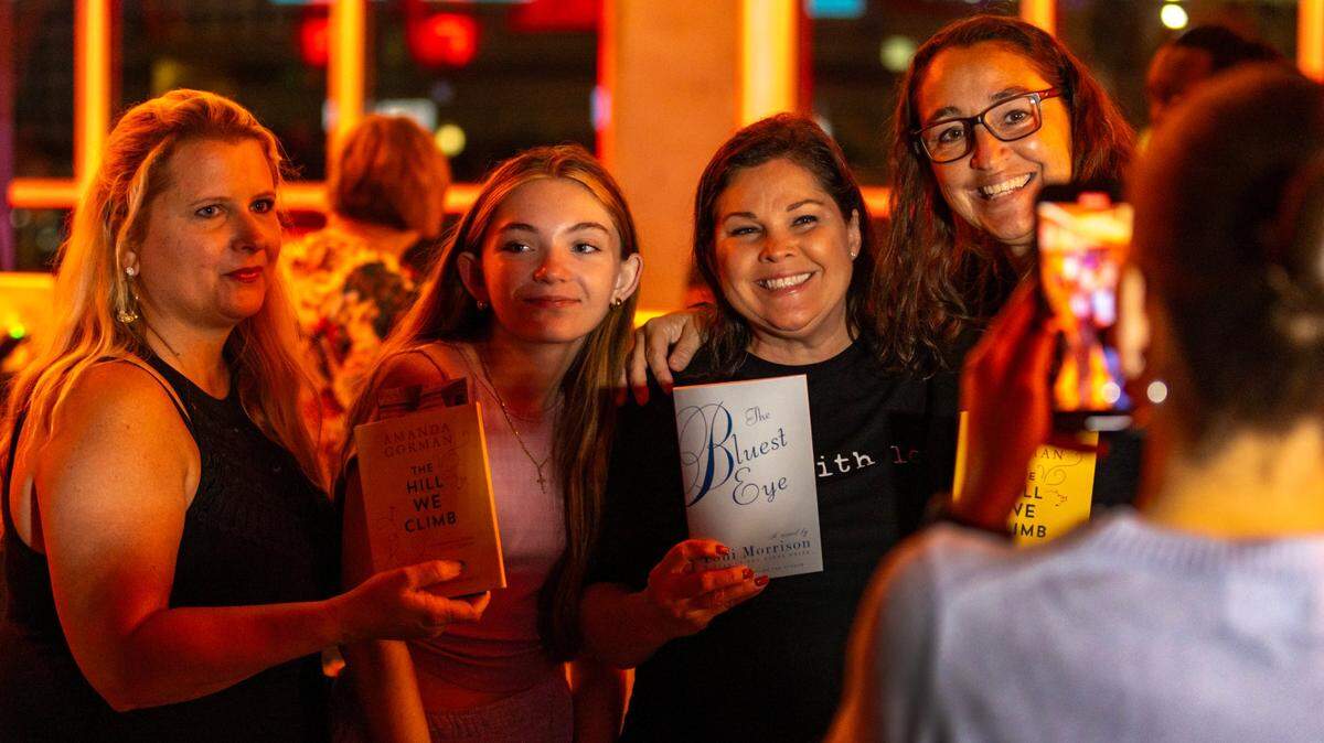 Sylvia Saco, left, holds up a copy of the book, ‘The Hill We Climb,’ by inaugural poet Amanda Gorman. Pink gave away 1,000 copies of four books, including Gorman’s book, that some school districts have banned. The giveaway was during her concert in Miami Tuesday night, Nov. 14, 2023. Saco is a middle school teacher.