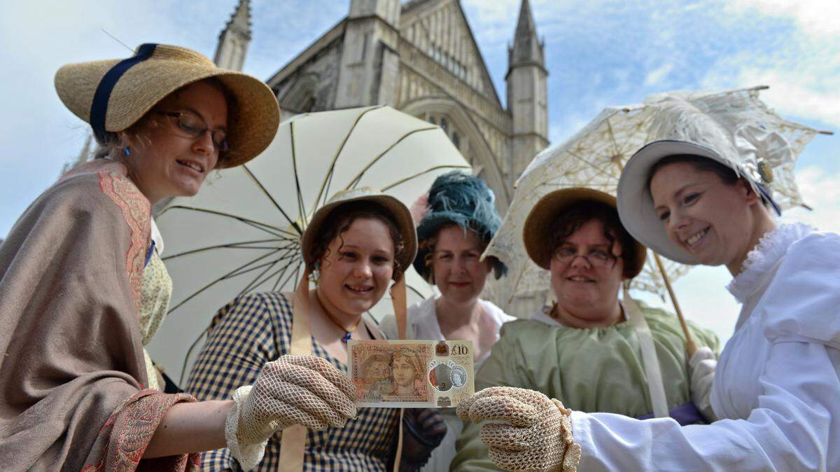People in period costume pose with one of the Bank of England’s new ten pound notes, featuring British author Jane Austen, during its unveiling at Winchester Cathedral on July 18, 2017 in Winchester, England.