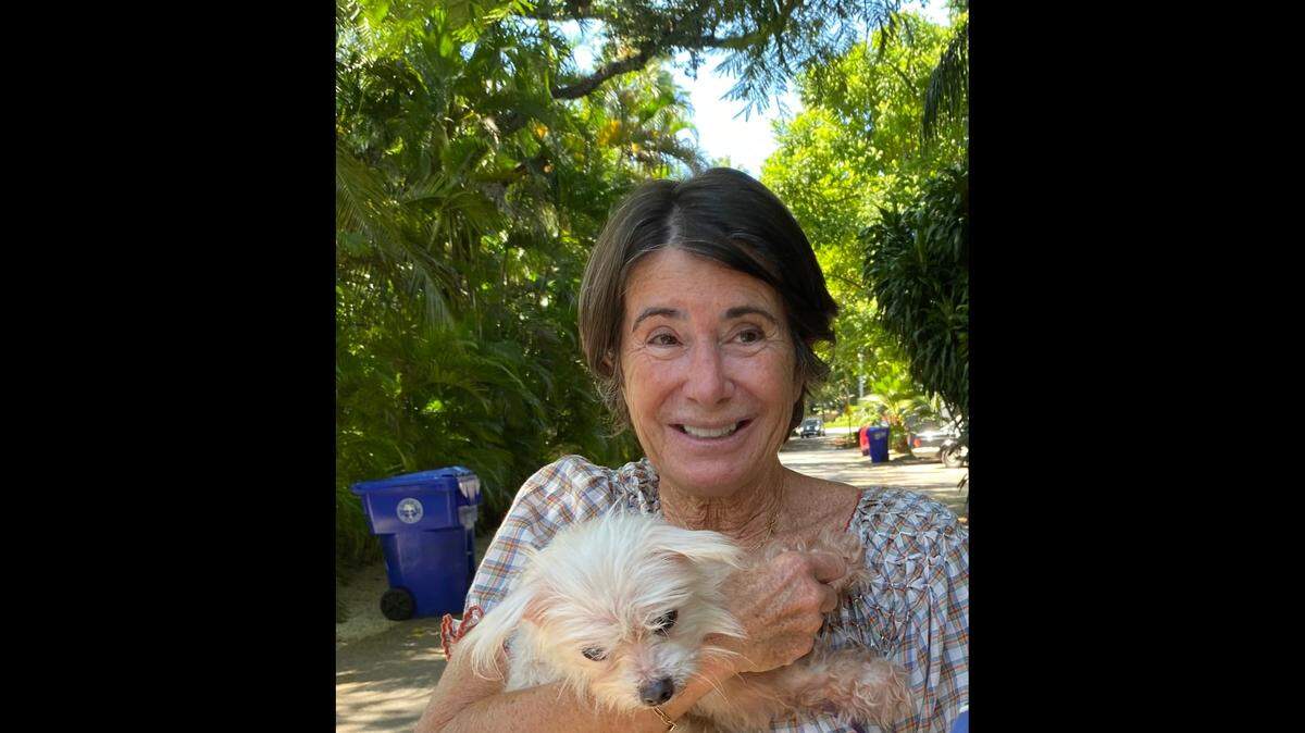 Brigitte Bourgoignie, 65, smiles with her pet, Sissi, after being reunited Thursday afternoon. Bourgoignie had not seen her Maltese in 7 years.