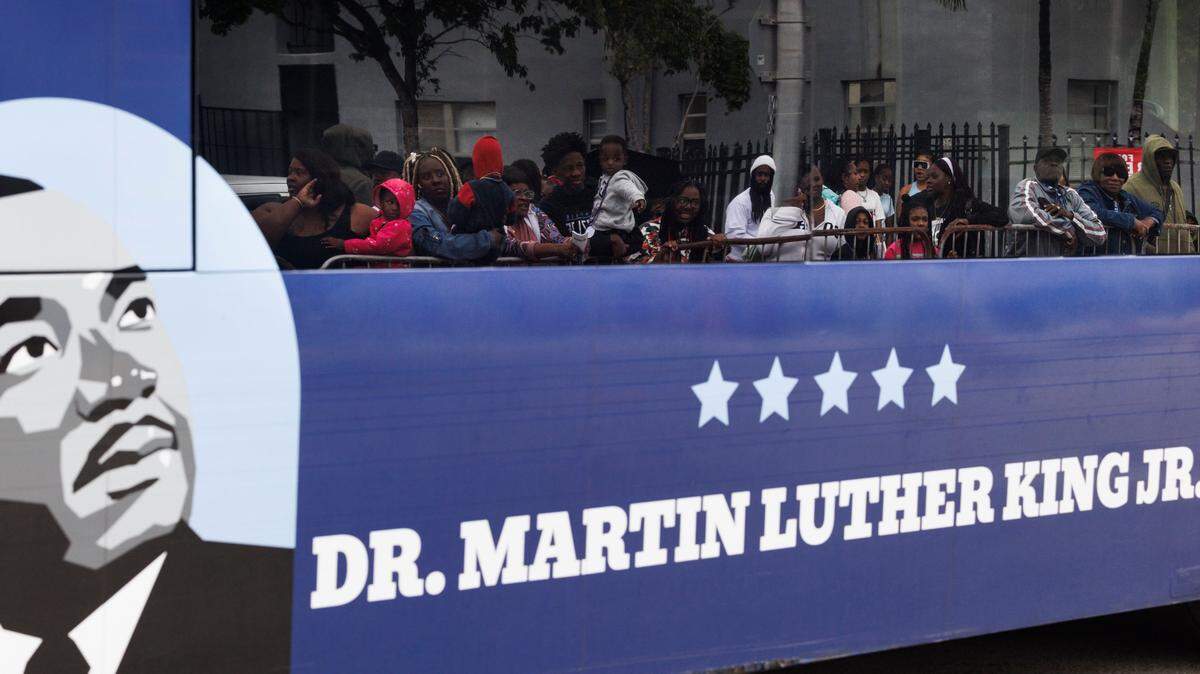 The reflection of parade attendees is seen through a buss driving in the Dr. Martin Luther King Jr. Day parade on Monday, Jan. 20, 2025, in Liberty City in Miami, Fla. 