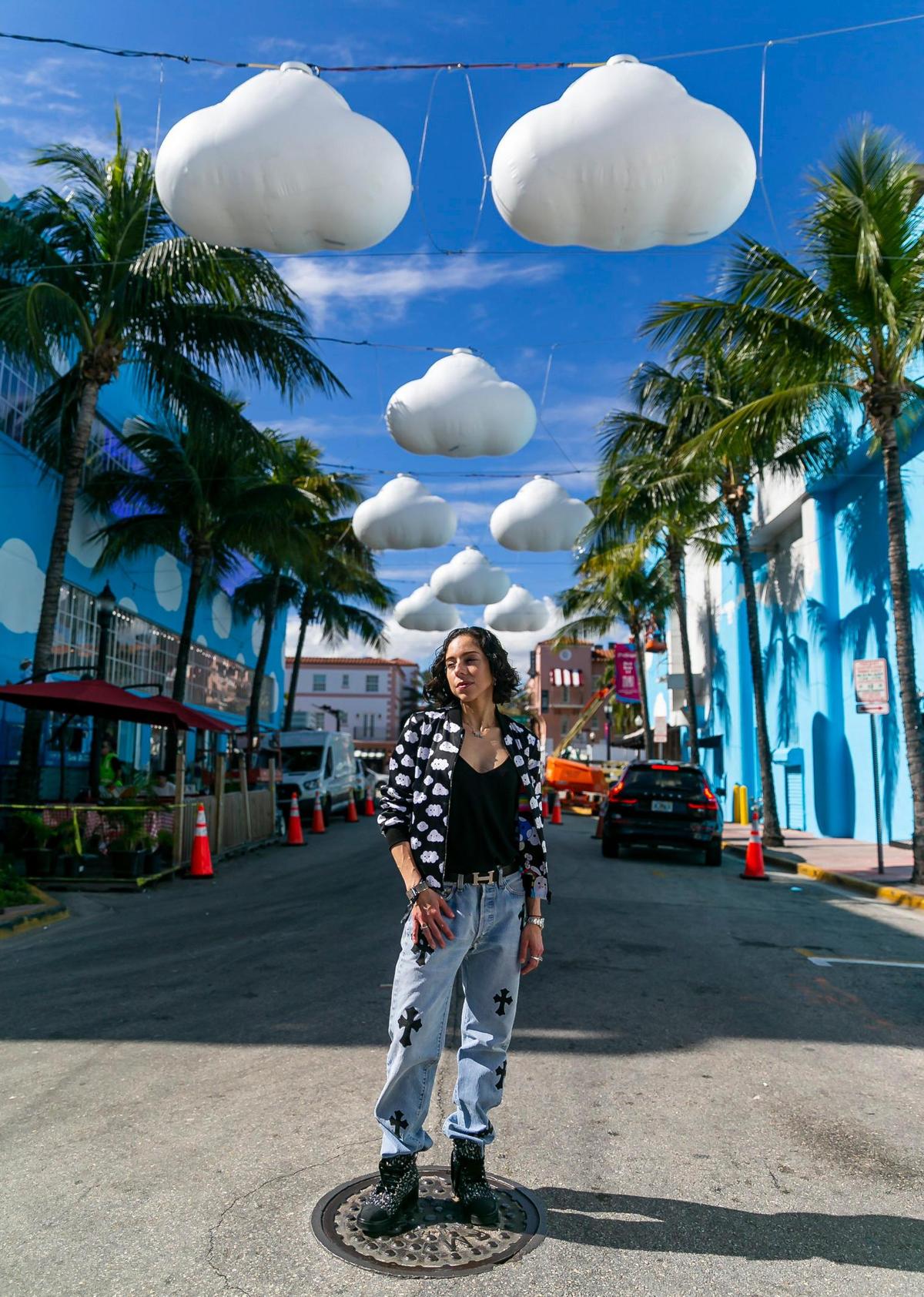 Lina Kandel, que está de visita desde Denver, es fotografiada debajo de Little Cloud Sky por FriendsWithYou cerca de Washington Avenue y Española Way en Miami Beach, Florida, el martes 30 de noviembre de 2021.