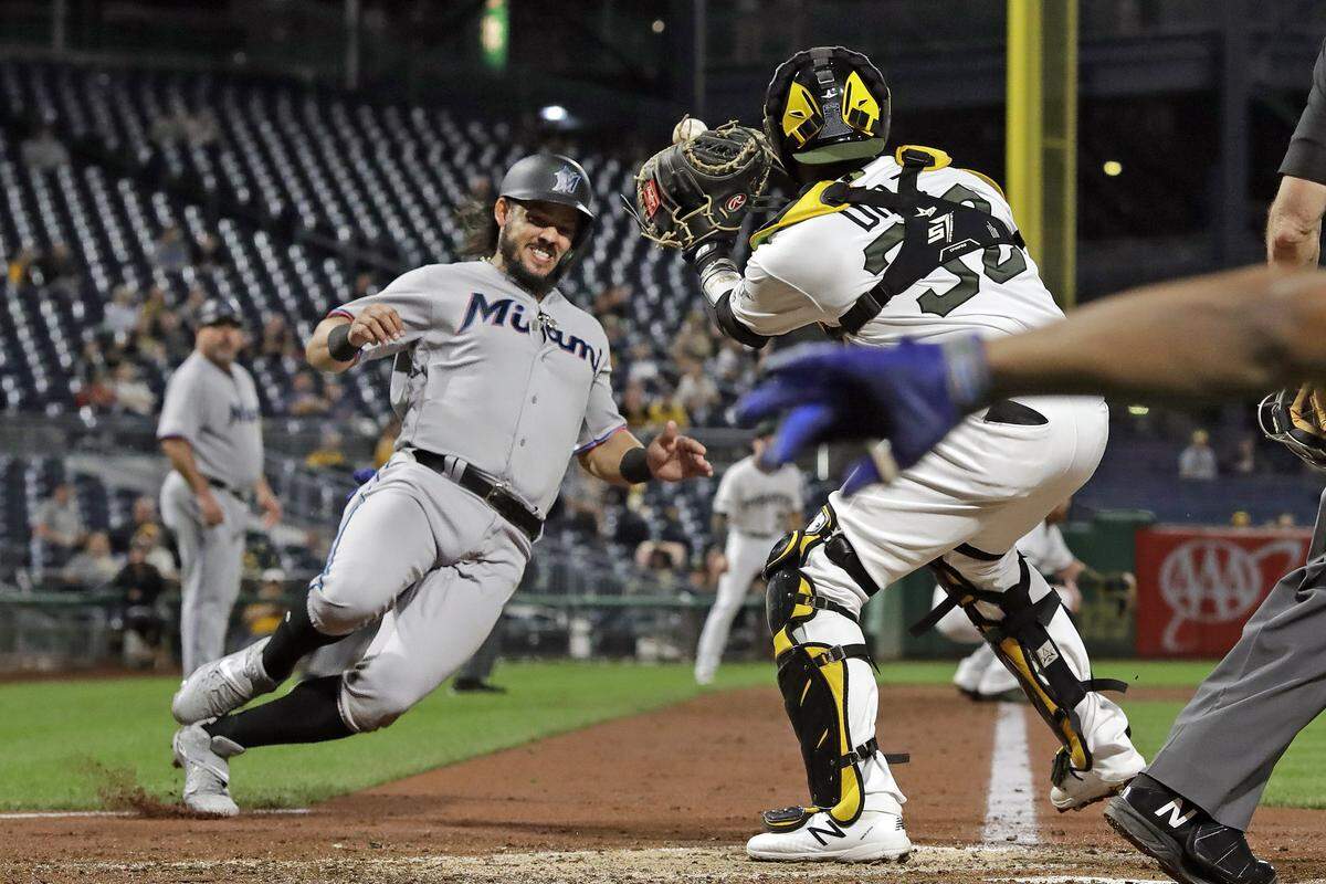 Miami Marlins’ Jorge Alfaro, left, begins his slide as Pittsburgh Pirates catcher Elias Diaz receives the relay throw during the fifth inning of a baseball game in Pittsburgh, Thursday, Sept. 5, 2019. Diaz had the ball knocked out of his glove and Alfaro was safe on the play. (AP Photo/Gene J. Puskar)