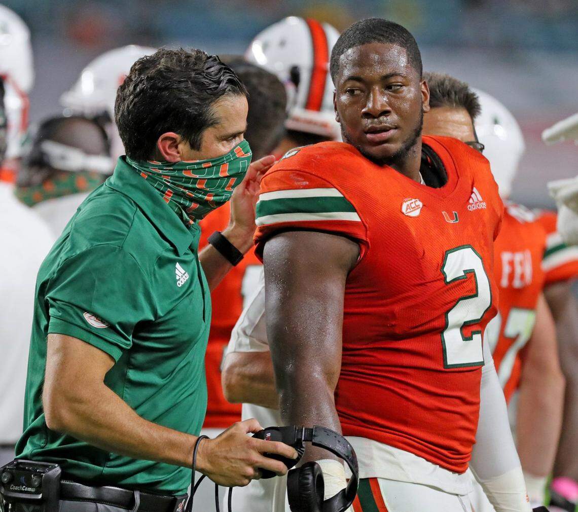 Miami Hurricanes coach Manny Diaz talks with defensive lineman Quincy Roche (2) as they play the Virginia Cavaliers at Hard Rock Stadium in Miami Gardens, Florida, Saturday, October 24, 2020.