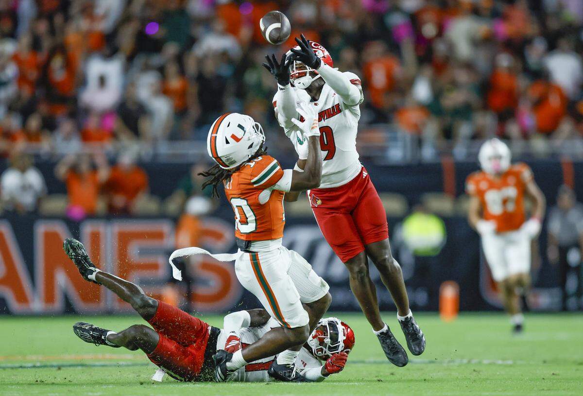 Louisville Cardinals defensive back Antonio Watts (9) intercepts the pass intended for Miami Hurricanes wide receiver Malachi Toney (10) during their NCAA football game at Hard Rock Stadium in Miami Gardens, Florida, on Friday, October 17, 2025.