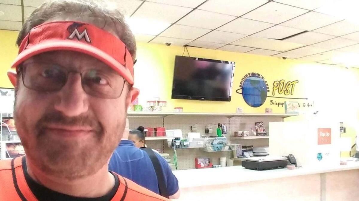 Laurence Leavy, a Fort Lauderdale lawyer best known as the "Marlins Man" for wearing an orange team jersey in the front row of major sporting events, poses for a selfie in a post office in the British Virgin Islans. Lawyers for the Miami Marlins sought to have a Miami-Dade lawsuit bumped to federal court over that post office, the home of a corporation that owns a portion of the team. The Marlins claimed that ownership entitled it to international arbitration. Miami-Dade lawyers rejected that claim, and used the Leavy selfie as an exhibit in a recent court filing.