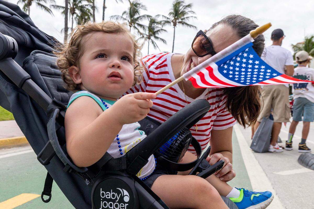 Matthew Bracco, 14 months, watches the parade participants drive and march up Ocean Drive as his mother Nancy reacts during the 16th Annual Veterans Day Parade on Monday, Nov. 11, 2024, in Miami Beach, Fla.