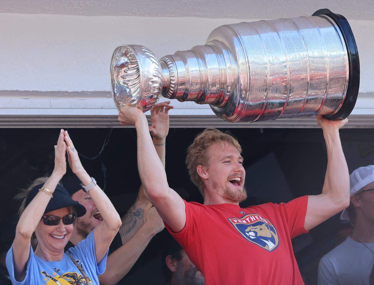 Gustav Forsling raises the trophy over his head to the cheers of fans on the balcony of the Elbo Room in Fort Lauderdale after the Florida Panthers won the Stanley Cup Final for the second time on Wednesday, June 18, 2025.