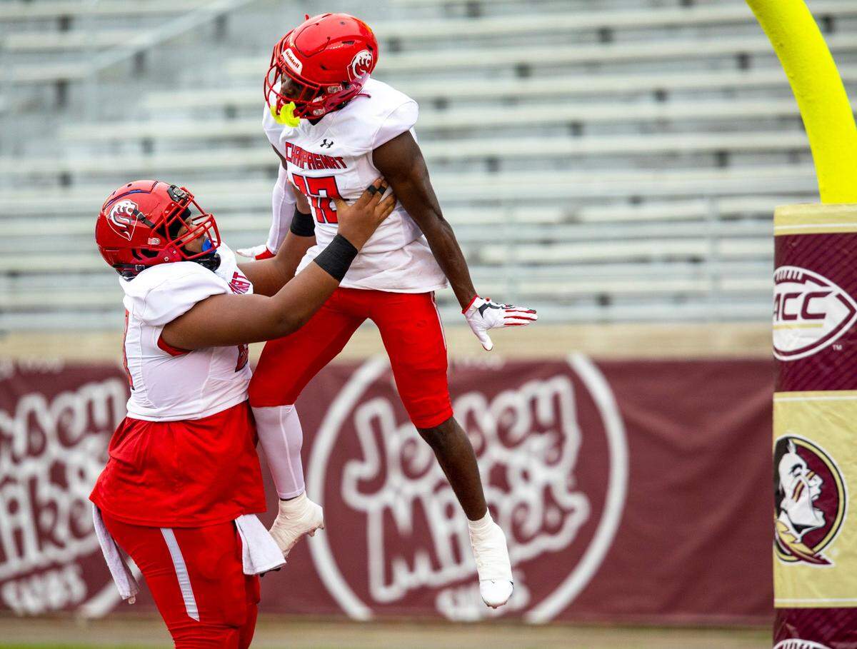 Champagnat Catholic Lions wide receiver Benson Prosper (12) is lifted into the air by his lineman, after scoring against University Christian Christians defenders, during the first half of the 2A State Championship at Doak Campbell Stadium in Tallahassee, Florida, on Wednesday, December 16, 2020.