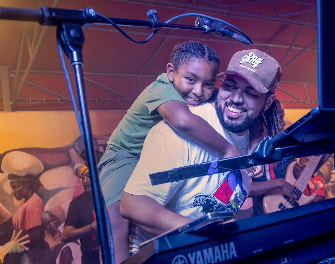 KAI keyboardist plays with his daughter on his back on Friday, June 20, 2025, at “Sounds of Little Haiti” at the Little Haiti Cultural Complex.