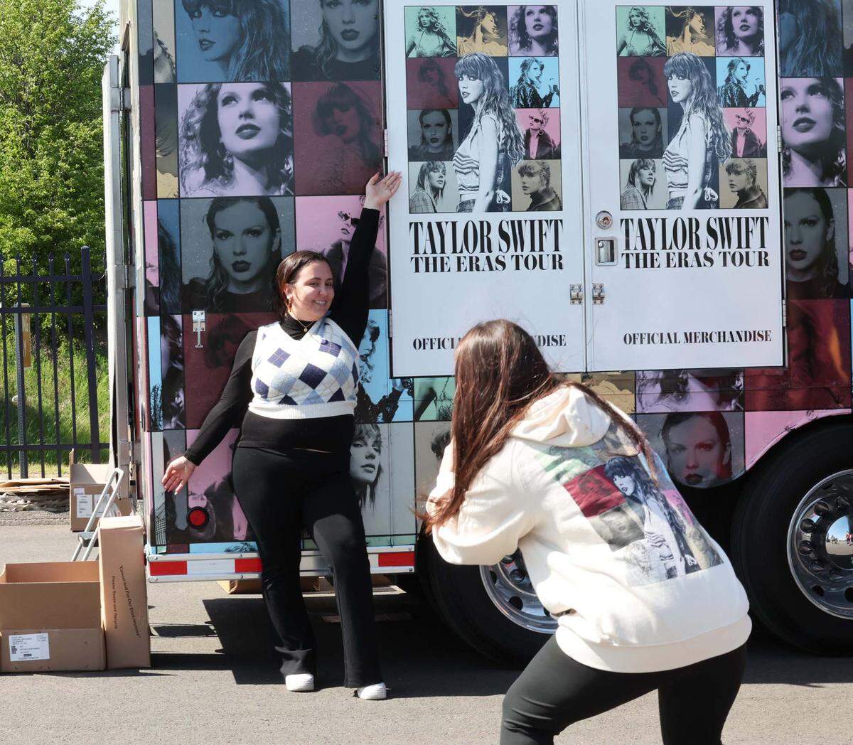 A fan poses next to the Taylor Swift merchandise trailer.