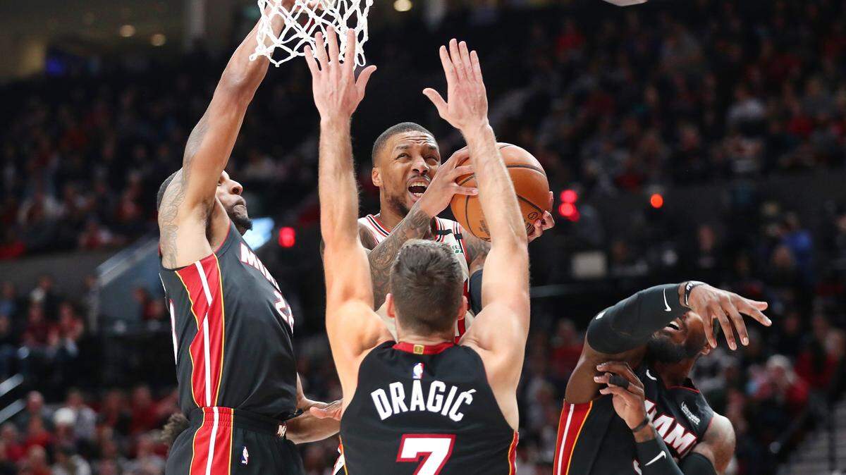 Los jugadores del Heat Derrick Jones (izq.), Goran Dragic y Jae Crowder (der.) tratan de impedir la canasta de Damian Lillard (0) de los Trail Blazers el 9 de febrero en Portland, Oregon.