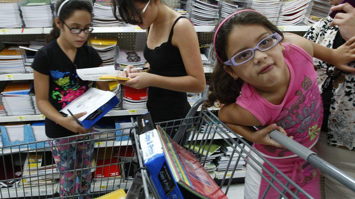 En esta foto de archivo del 12 de agosto de 2009, estudiantes de primaria y su madre compraron útiles escolares en un Walmart del sur de Florida.