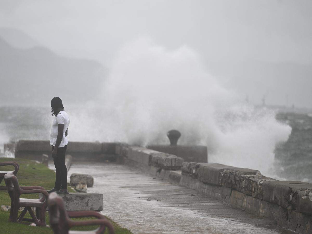 A man watches the waves crash into the walls at the Kingston Waterfront on October 27, 2025. Hurricane Melissa threatened Jamaica with potentially deadly rains after rapidly intensifying into a top-level Category 5 storm, as residents scrambled for shelter from what could be the island's most violent weather on record. Melissa has already been blamed for at least four deaths in Haiti and the Dominican Republic, and was set to unleash torrential rains on parts of Jamaica in a direct hit on the Caribbean island.