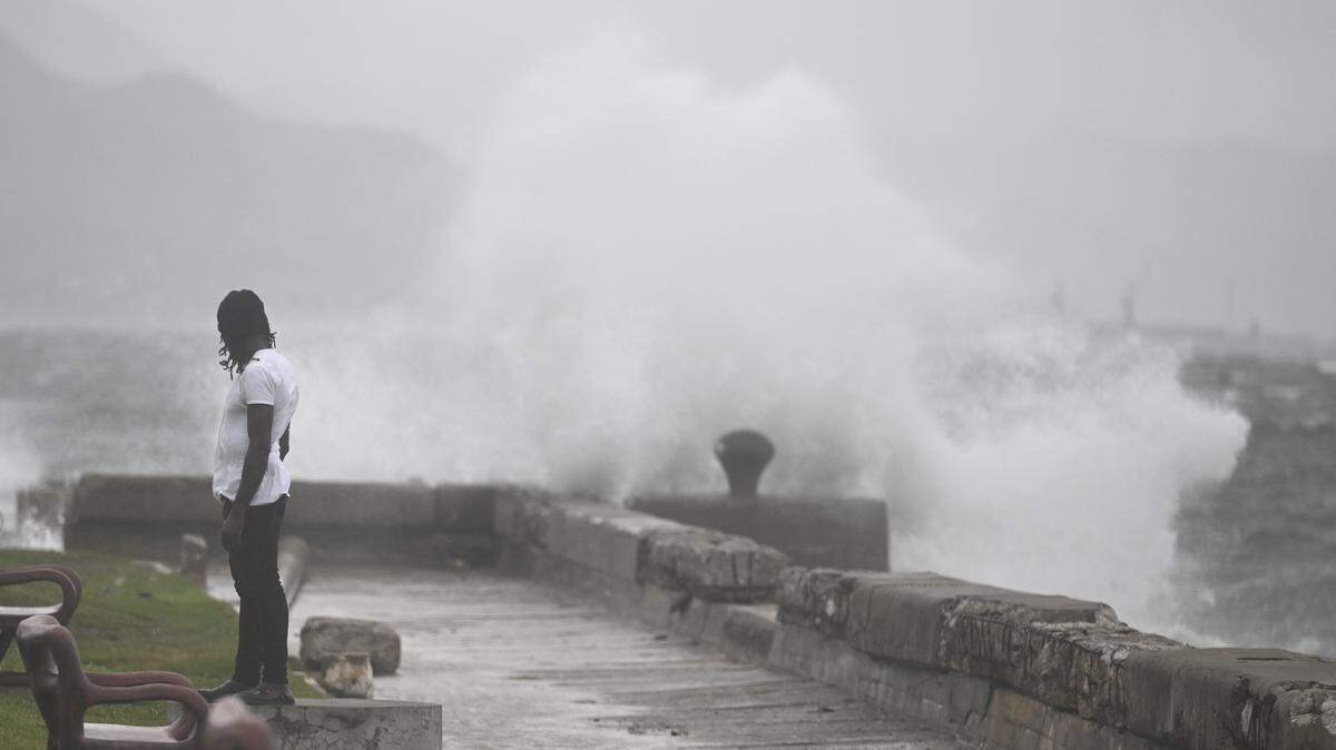A man watches waves crash into the walls at the Kingston Waterfront on October 27, 2025. Hurricane Melissa threatened Jamaica with potentially deadly rains after rapidly intensifying into a top-level Category 5 storm, as residents scrambled for shelter from what could be the island's most violent weather on record. (Photo by RICARDO MAKYN/AFP via Getty Images)          