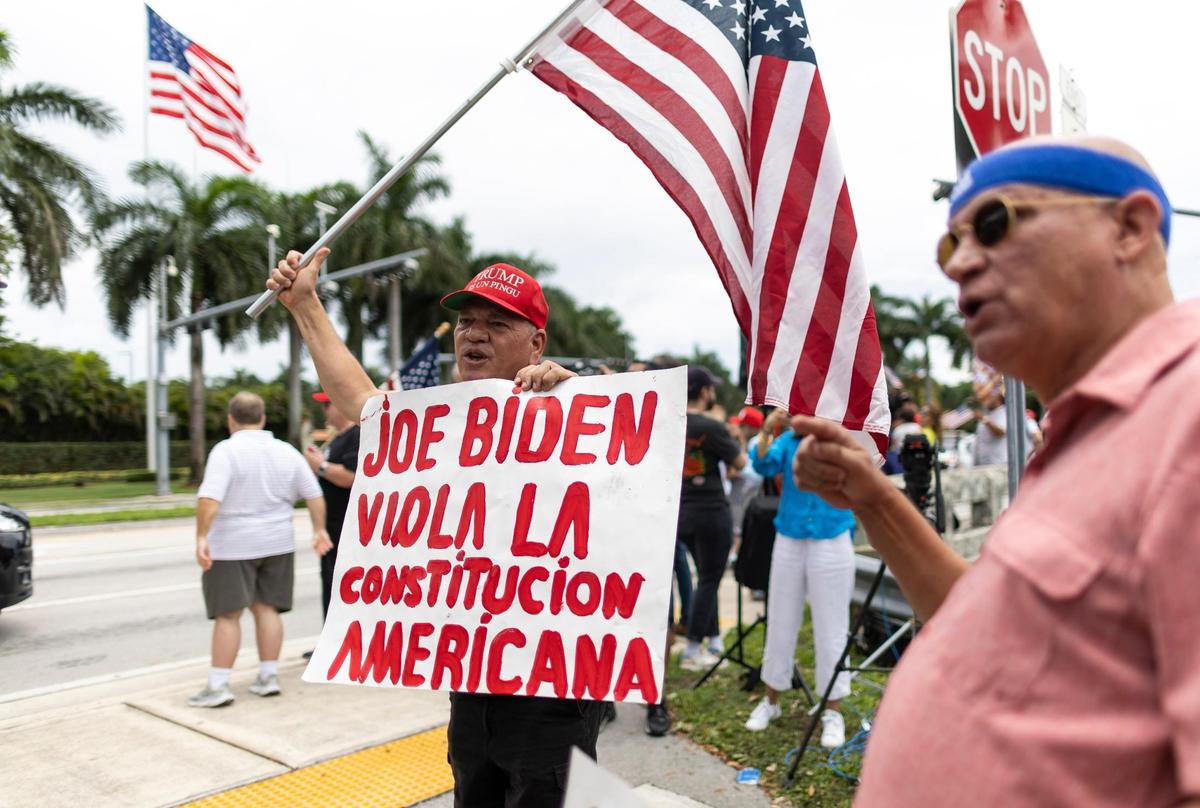 Joel Talavera, center, holds a flag and a sign while standing outside of Trump National Doral on Monday, June 12, 2023, in Doral, Fla. Supporters of former President Donald Trump gathered outside his hotel one day before his expected arraignment in Miami federal court on Tuesday. Trump was indicted last week on federal criminal charges related to his handling of classified documents..