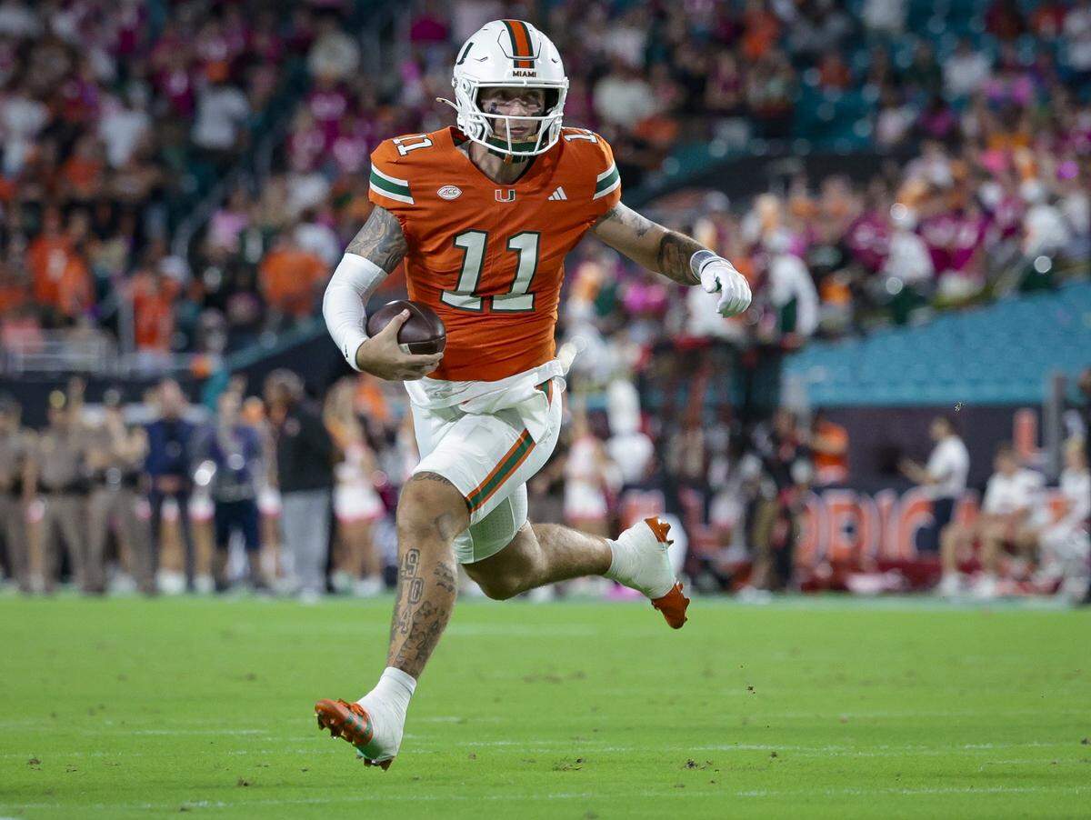 Miami Hurricanes quarterback Carson Beck (11) scrambles towards the endzone during the NCAA football game against the Louisville Cardinals at Hard Rock Stadium in Miami Gardens, Florida, on Friday, October 17, 2025.