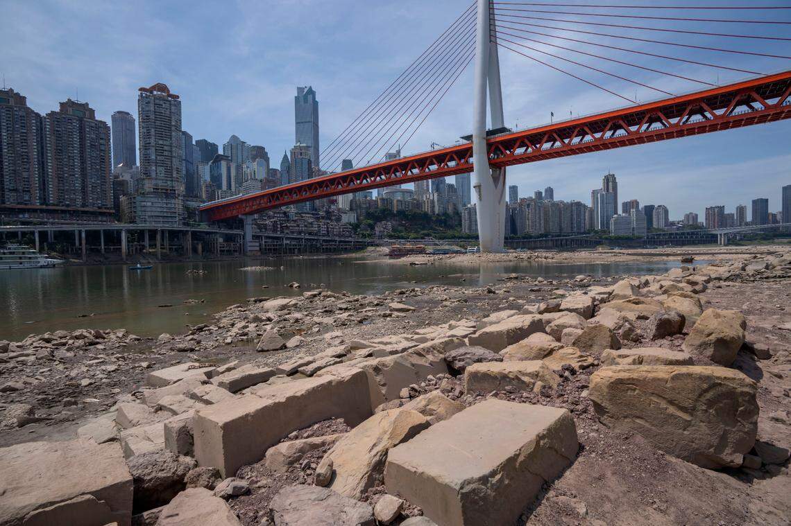 Rocks are exposed on the dry riverbed of the Jialing River in southwestern China’s Chongqing Municipality, Friday, Aug. 19, 2022. Ships crept down the middle of the Yangtze on Friday after the driest summer in six decades left one of the mightiest rivers shrunk to barely half its normal width and set off a scramble to contain damage to a weak economy in a politically sensitive year. (AP Photo/Mark Schiefelbein)