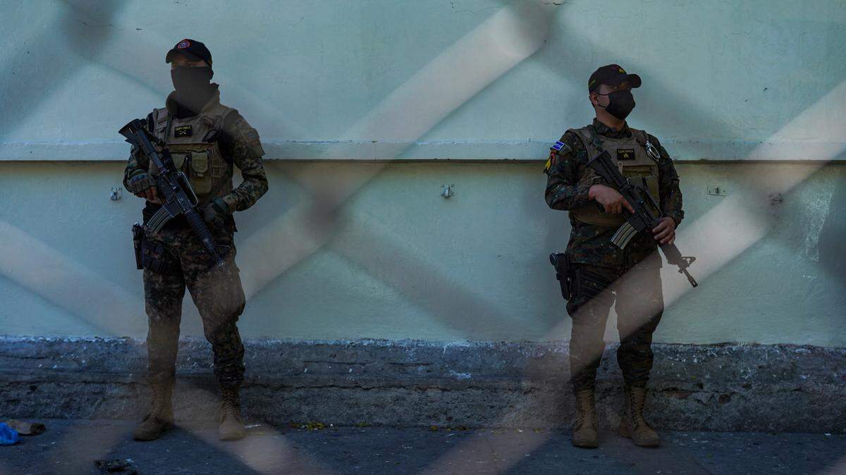 In December 2022, soldiers stand guard at a checkpoint in the Tutunichapa Community, a popular point for drug trafficking in the Salvadoran capital, as part of the Salvadoran government’s state of emergency.