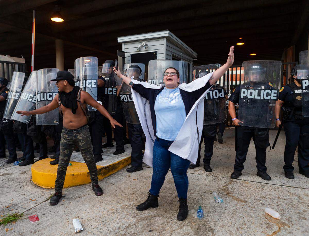 Activists try to calm the crowd as some throw objects toward police during a ‘Justice for George Floyd’ protest in downtown Miami.