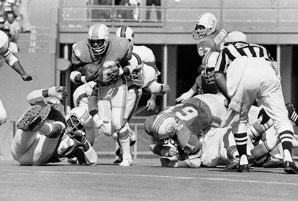 Miami running back Hubert Ginn picks his way past his blockers to gain against Buffalo in first quarter of game at the Orange Bowl in Miami, on Sunday, Nov. 8, 1971. Blocking at right is Bob DeMarco (61), the Miami Center. Miami won 34-0. (AP Photo)