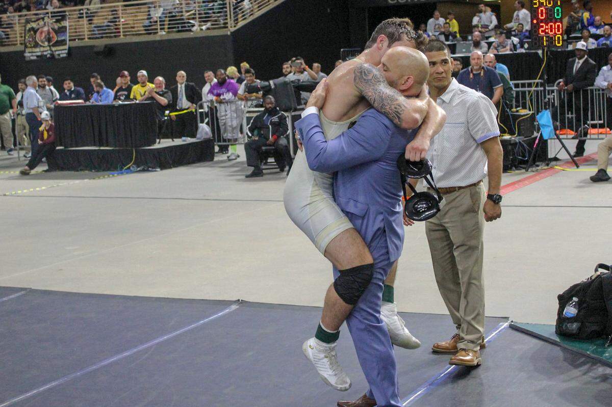 South Dade wrestling coach Vic Balmeceda hugs his son, Brevin Balmeceda, after Brevin wins the individual title in the Class 3A 162 lbs division at the 2019 FHSAA state wrestling championship on Saturday, March 9, 2019, at Silver Spurs Arena in Kissimmee, Florida.