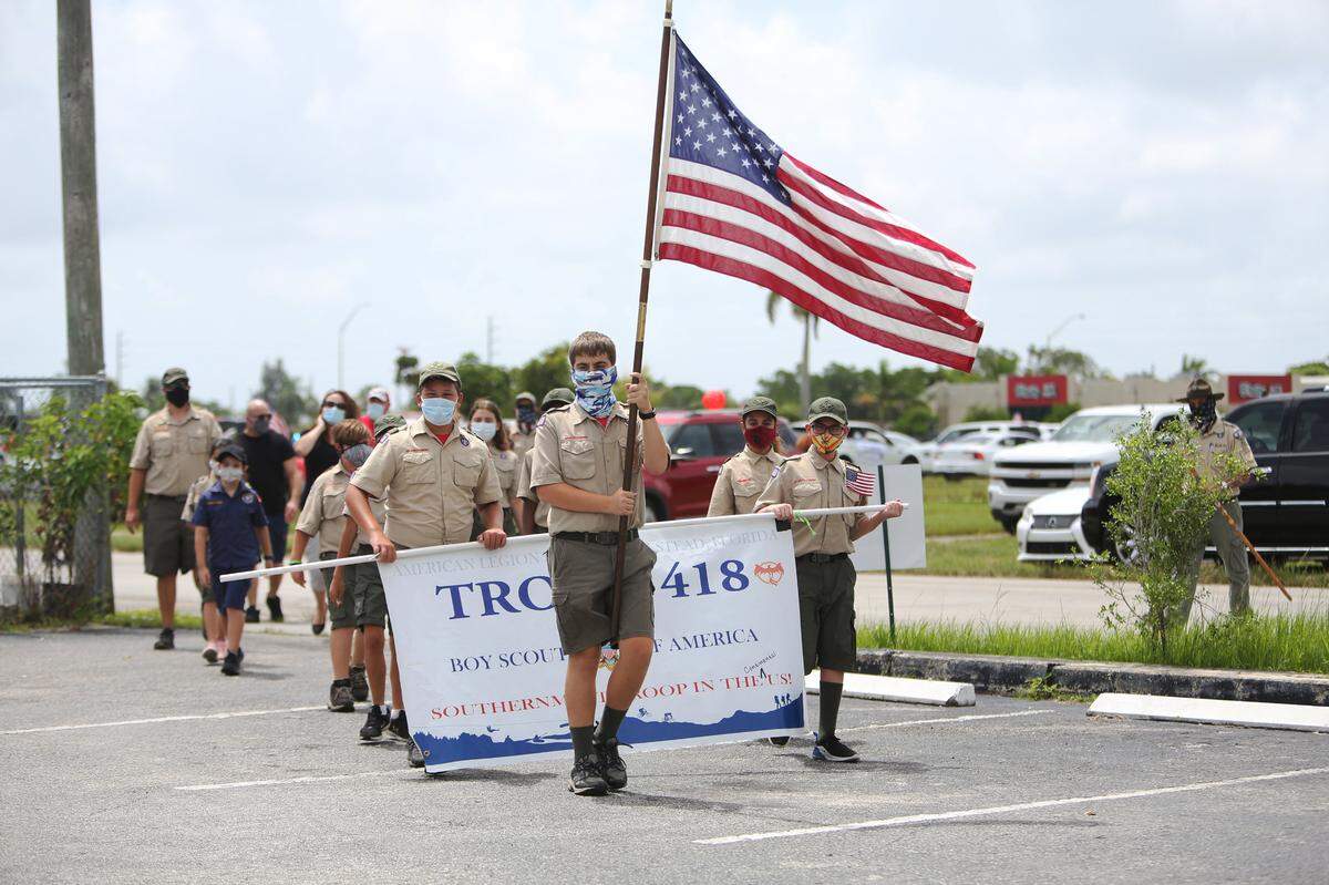 Boy Scout Troop 418 marches by as part of the surprise 99th birthday caravan celebration for John Hatcher in front of the American Legion.