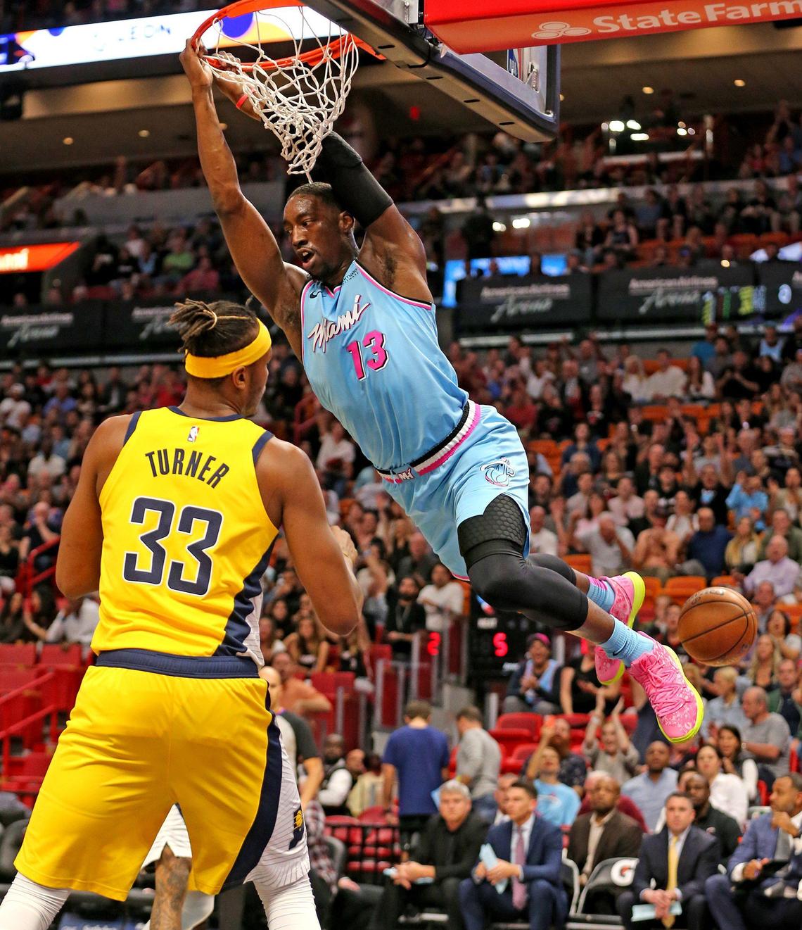 Miami Heat Bam Adebayo (13) swings on the rim after a dunk in the first quarter as Indiana Pacers Myles Turner (330 watches at the AmericanAirlines Arena in Miami, Florida, Friday, December, 27, 2019.