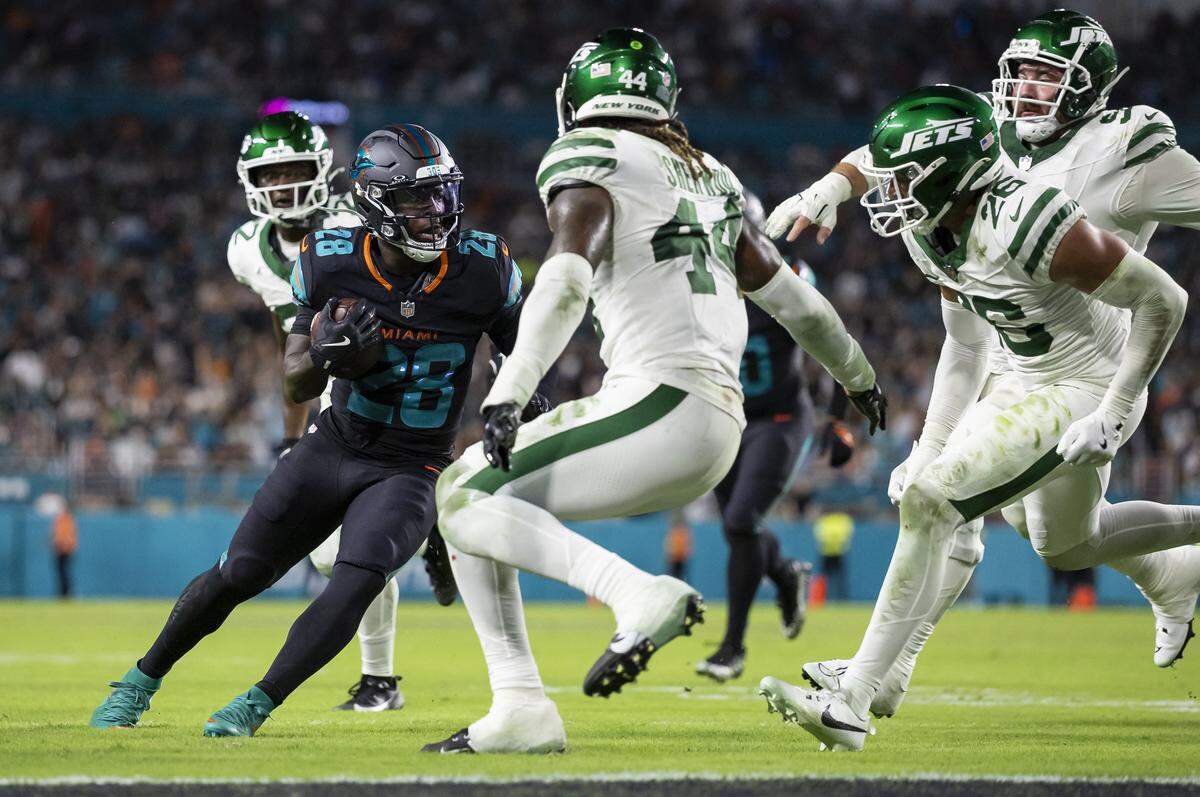 Miami Dolphins running back De'von Achane (28) runs with the ball as New York Jets linebacker Jamien Sherwood (44) tries to tackle him in the second half of their NFL game at Hard Rock Stadium on Monday, Sept. 29, 2025, in Miami Gardens, Fla.