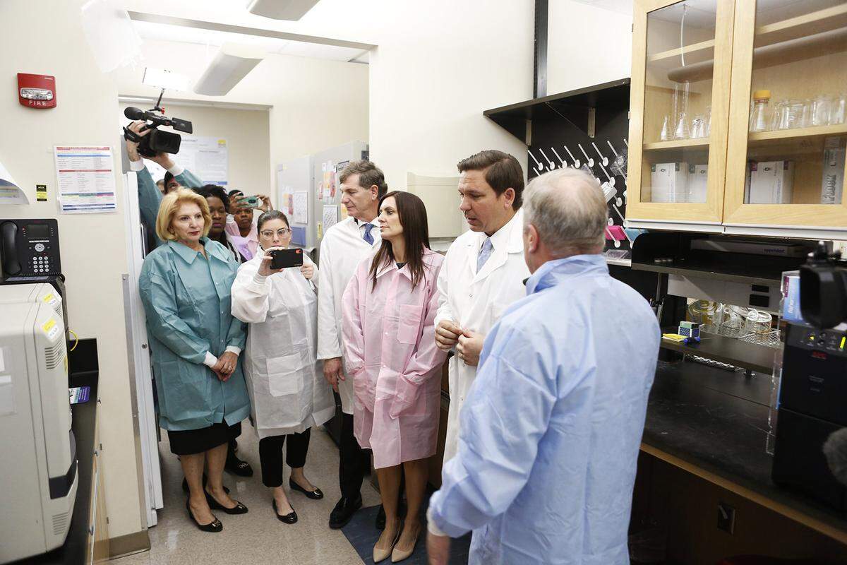 From left, Deputy Secretary for Health Shamarial Roberson, state Sen. Janet Cruz, Surgeon General Dr. Scott Rivkees, Lieutenant Governor Jeanette Núñez and Governor Ron DeSantis look on while Andrew Cannons, laboratory director at the Bureau of Public Health Laboratories, explains the testing procedures of potential coronavirus cases on Monday, March 2, 2020 at the Florida Department of Health laboratory in Tampa.