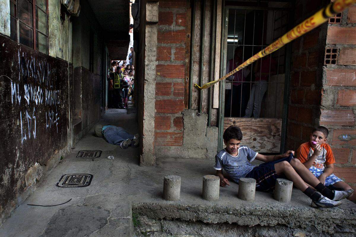 A couple of children eat ice cream at a crime scene, while forensic police investigate in Medellin, Colombia.  Medellin has become a violent city because of the internal war among drug cartels for the control of the local "plazas" or drug selling points.
