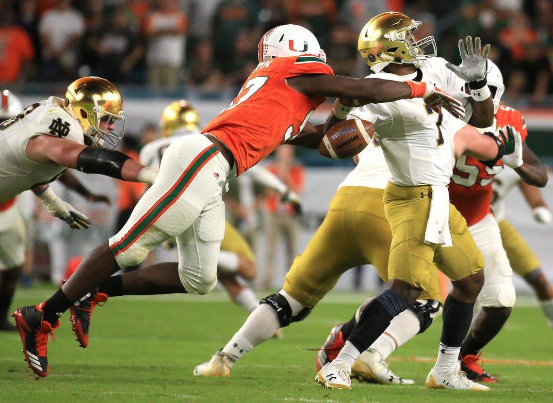 In 2017, Miami Hurricanes defensive lineman Jonathan Garvin knocks the ball out of Notre Dame Fighting Irish quarterback Brandon Wimbush for a fumble in the fourth quarter at Hard Rock Stadium.