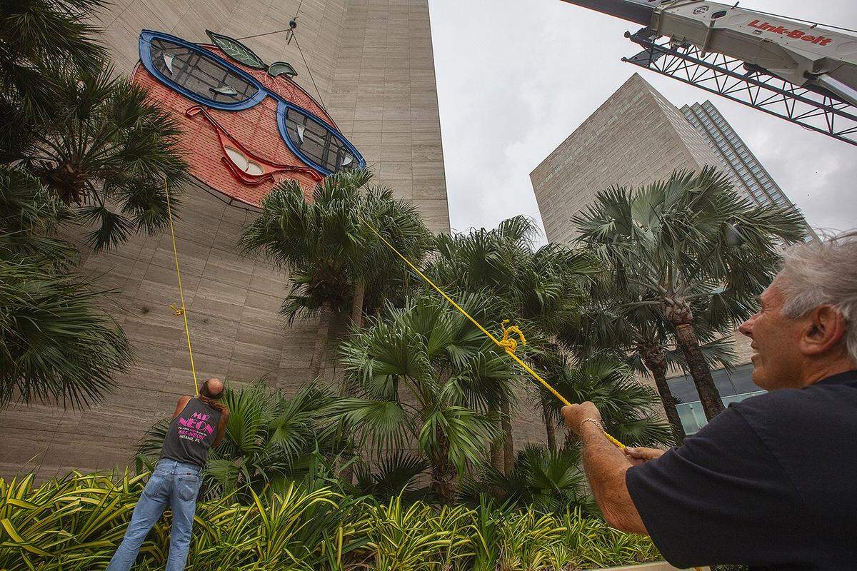 Bill Flaherty (center) assists “Mr. Neon” Steve Carpenter (right/front) with the Big Orange installation, a cherished Miami community New Year’s Eve tradition, on Friday, December 27, 2024, at the InterContinental Hotel in Downtown Miami.