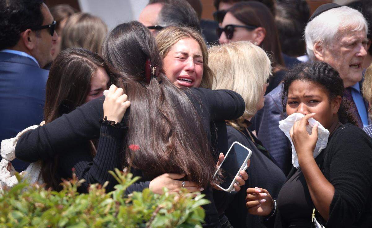 Amigos de la estudiante fallecida de Ransom Everglades, Ella Riley Adler, de 15 años, llorando y apoyándose mutuamente afuera de Temple Beth Sholom poco después del servicio funerario el lunes 13 de mayo de 2024, en Miami Beach, la Florida.