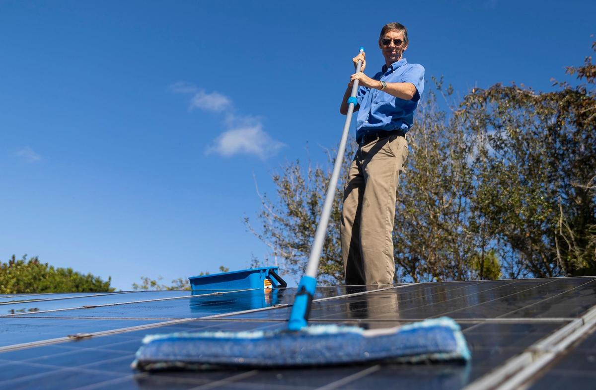 Phil Stoddard, presidente del Corredor Verde, limpiando los paneles solares de su tejado el miércoles 31 de enero de 2023, en South Miami, la Florida.