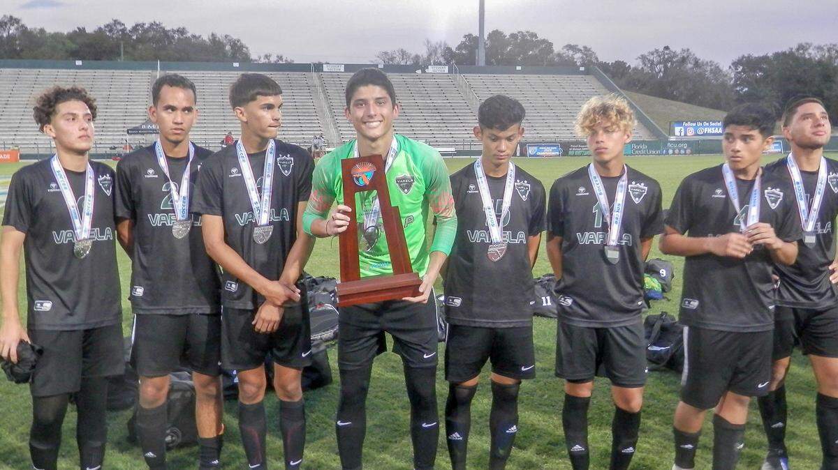 Surrounded by teammates, Varela goalkeeper Andres Jaramillo holds up the state runner-up trophy the Vipers had to settle for following a 2-1 loss to Lake Mary in the 5A state title game.