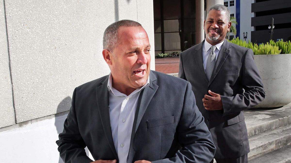 Luis Santiago, former Opa-locka city commissioner, exits the Federal Courthouse in Miami after surrendering to bribery charges in late 2016, while his defense attorney Roderick Vereen looks on.