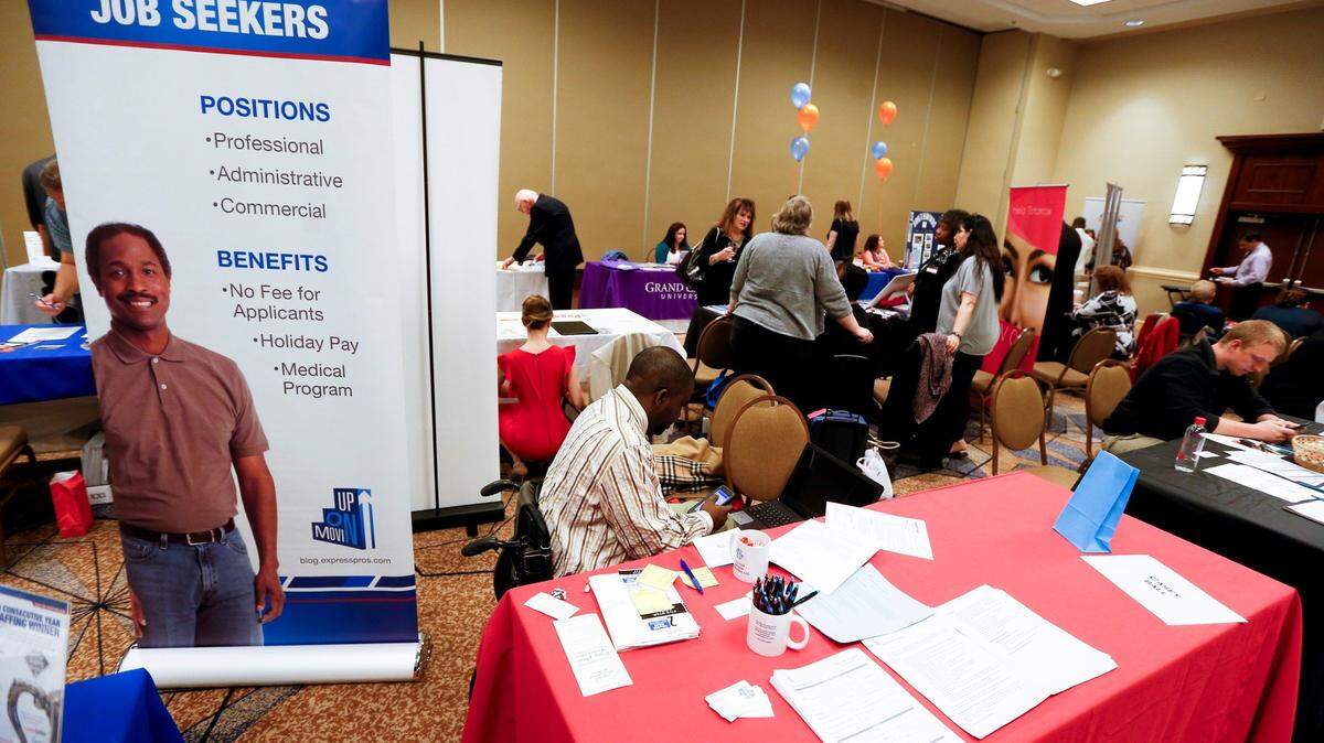 In this March 30, 2016, file photo, a sign designed to attract employment seekers stands next to a job recruiter’s booth at a job fair in Pittsburgh.
