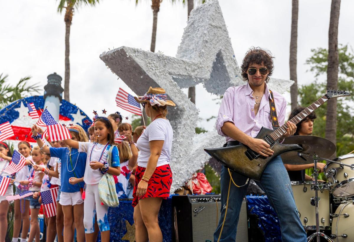 Parade participants wave flags and play music, celebrating Independence Day as they follow the parade route on Crandon Blvd, on Friday, July 4, 2025, in Key Biscayne, Fla.