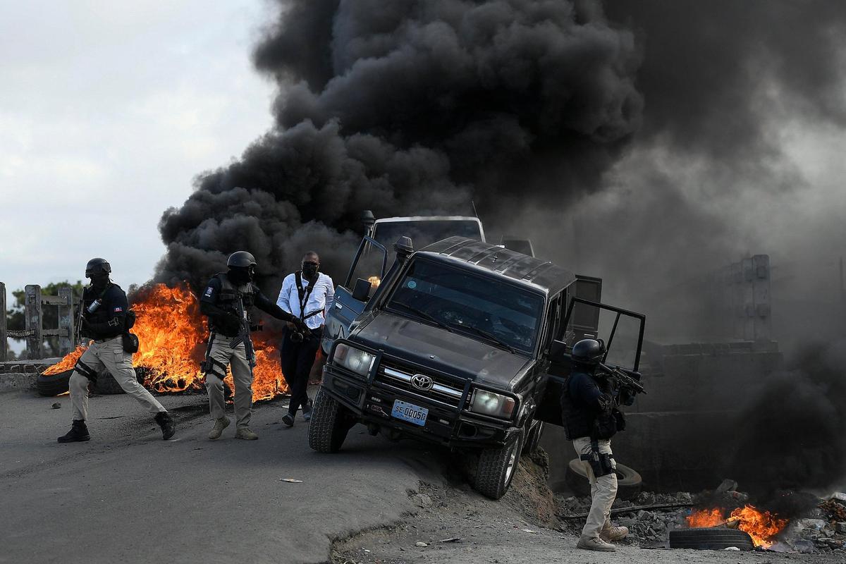 Police abandon their vehicle during a demonstration that turned violent in which protesters demanded justice for the assassinated President Jovenel Moïse in Cap-Haitien, Haiti, Thursday, July 22, 2021. Demonstrations after a memorial service for Moïse turned violent on Thursday afternoon with protesters shooting into the air, throwing rocks and overturning heavy concrete barricades next to the seashore as businesses closed and people took cover.