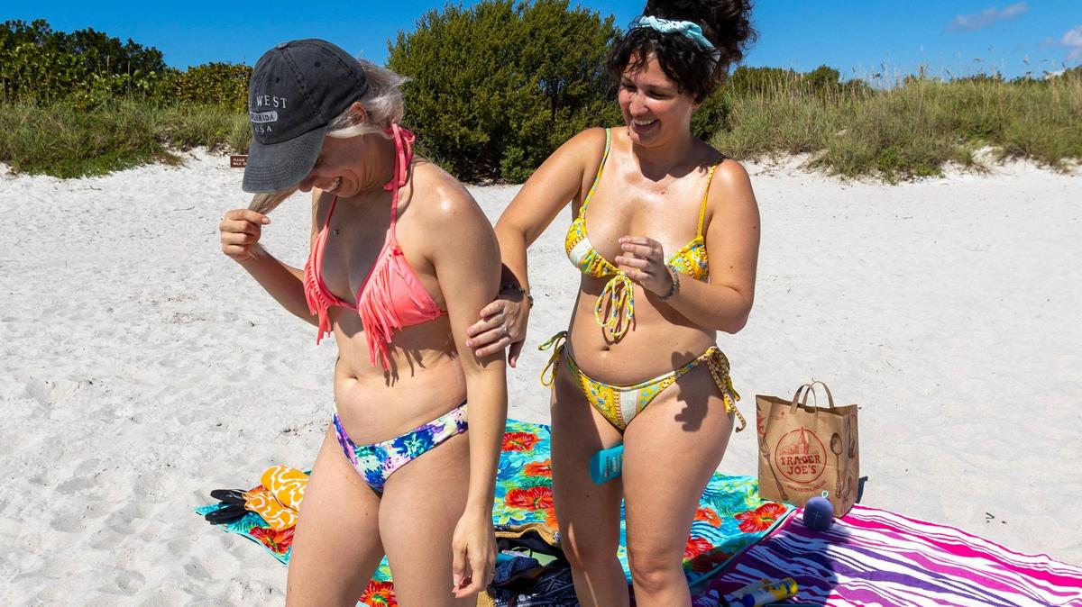 Alexandra Rincon, 33, helps Damarys Mendez, 36, apply sunscreen at Bill Baggs Cape Florida State Park in Key Biscayne, Florida, on Feb. 22, 2023. If you need added UV protection from the sun, you can layer sunscreens, but you need to know which sunscreens are compatible and what order to apply them, says Dr. Leslie Baumann.