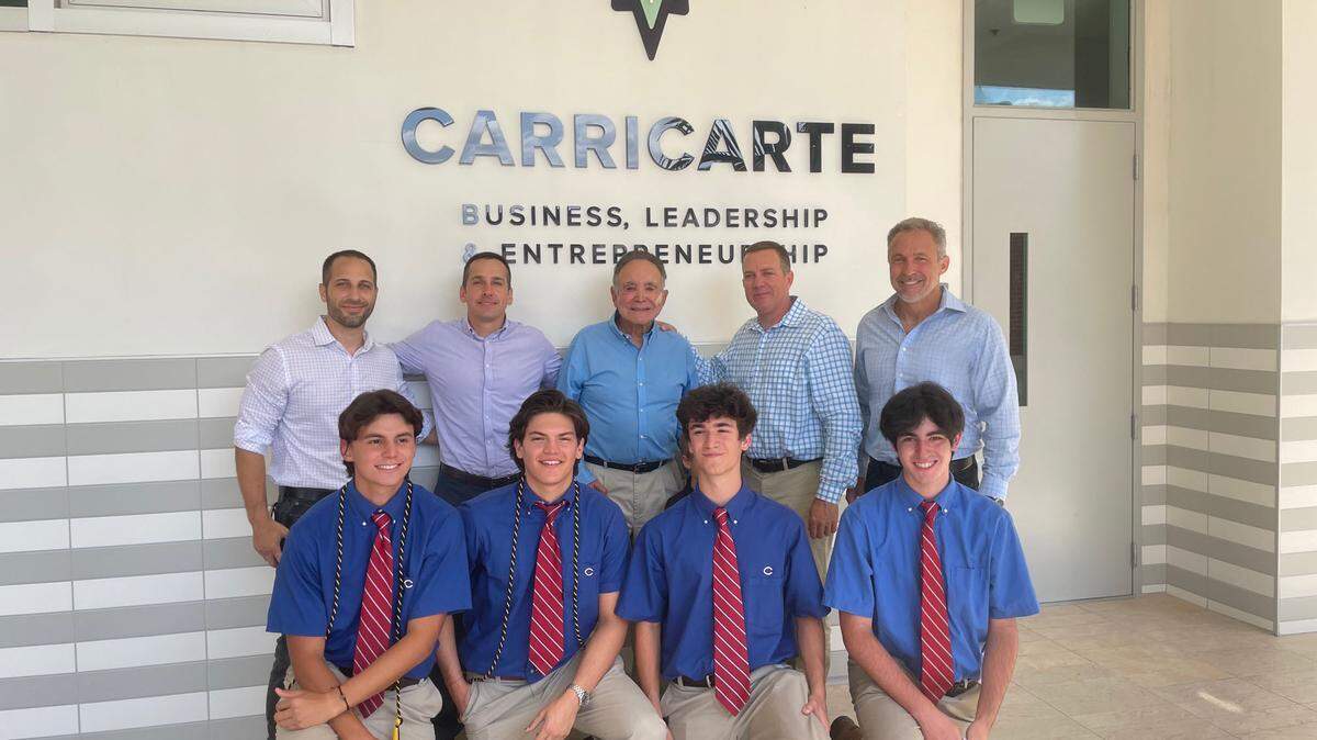 Members of the Carricarte family, back row, with Columbus High business students at the event on April 15 at which the new business program was unveiled. From left: Brian Carricarte, Andrew Carricarte, Mike Carricarte Sr., Louis Carricarte and Michael Carricarte Jr.